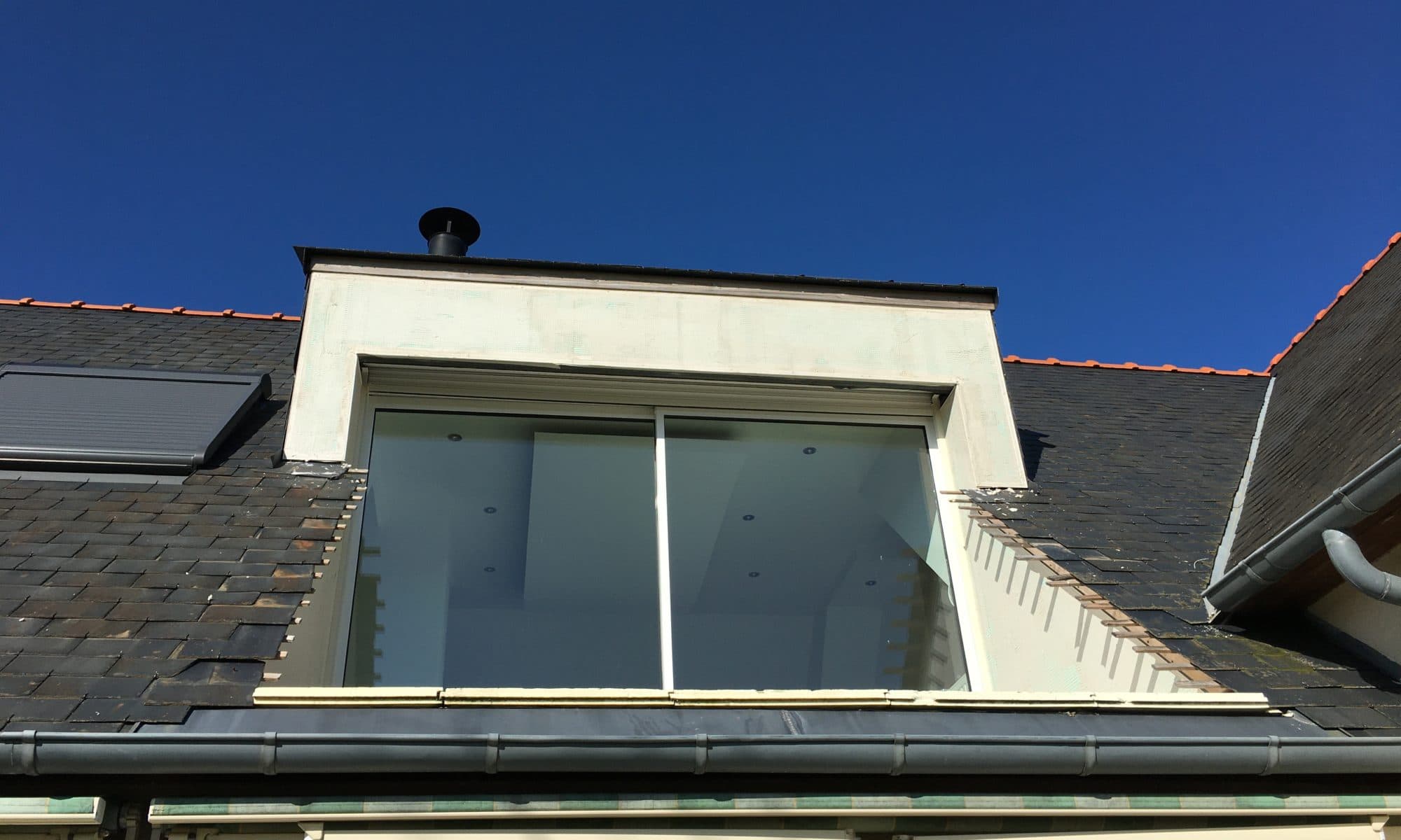 Fenêtre de toit moderne sous ciel bleu.